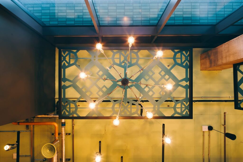 15 Fretwork panels echoing the reception desk front design are suspended from the ceiling above the chandeliers as well as creating subtle divisions of space